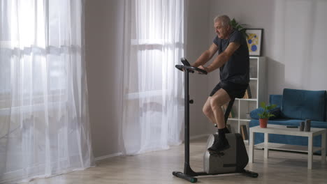 health-training-on-stationary-bike-middle-aged-man-is-spinning-pedals-exercise-for-breathing-and-cardiovascular-system-healthcare-and-sport